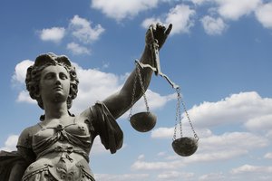 zu sehen ist eine weibliche Statur, die eine alte Waage in der Hand hält