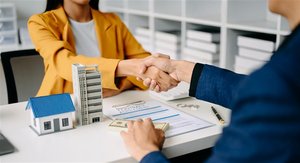 Eine Frau und ein Mann sitzen an einem Tisch gegenüber und geben sich die Hand