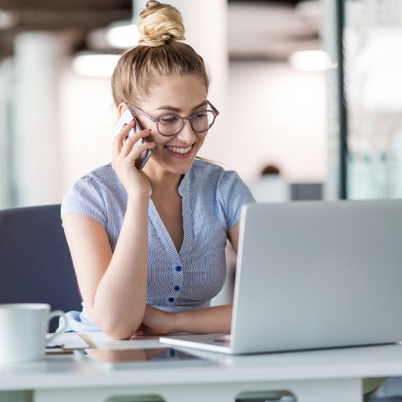 Eine junge Frau sitzt telefonierend am Computer