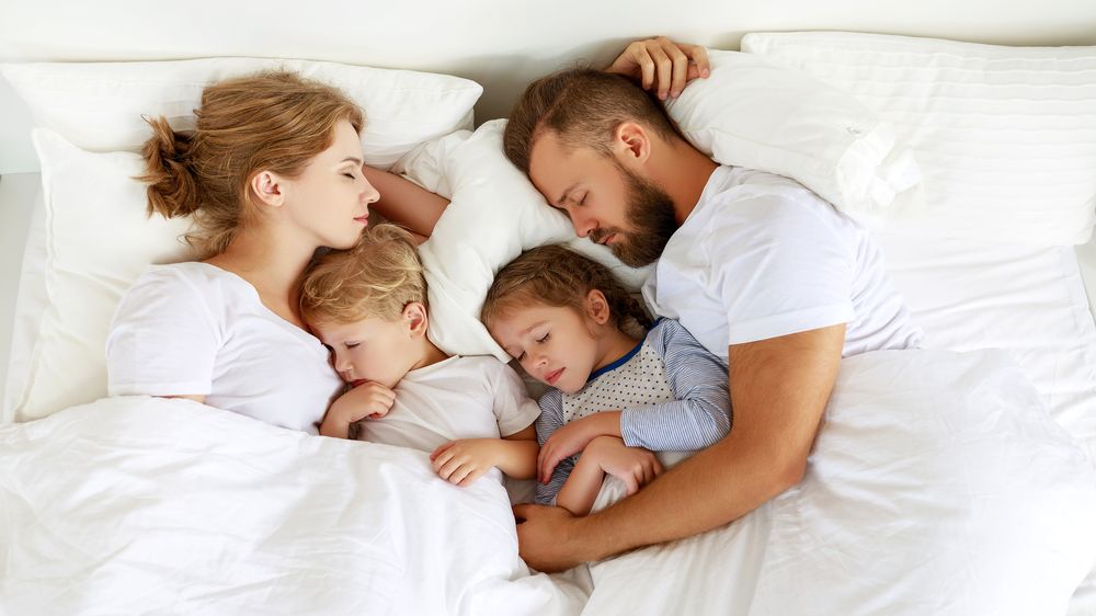 Kuschelnde Familie im Bett